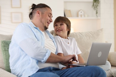 Photo of Father and his son watching something on laptop at home