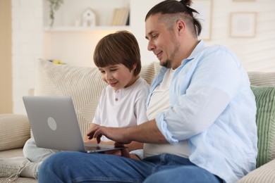 Photo of Father and his son watching something on laptop at home