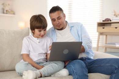 Photo of Father and his son watching something on laptop at home