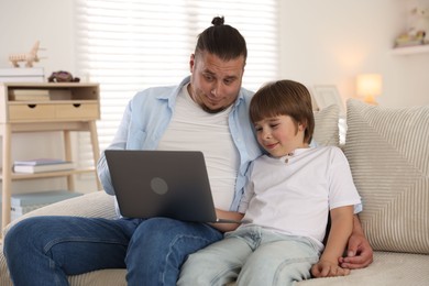 Photo of Father and his son watching something on laptop at home