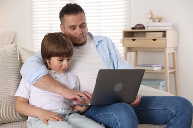 Photo of Father and his son watching something on laptop at home