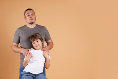 Photo of Father and his son on beige background, space for text