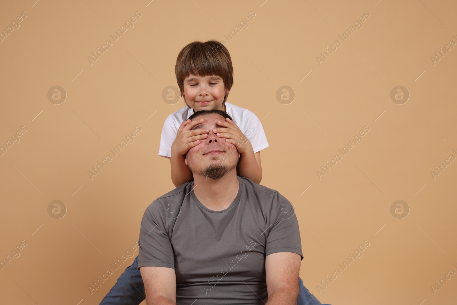 Father and his son on beige background Photo of Father and his son on beige background