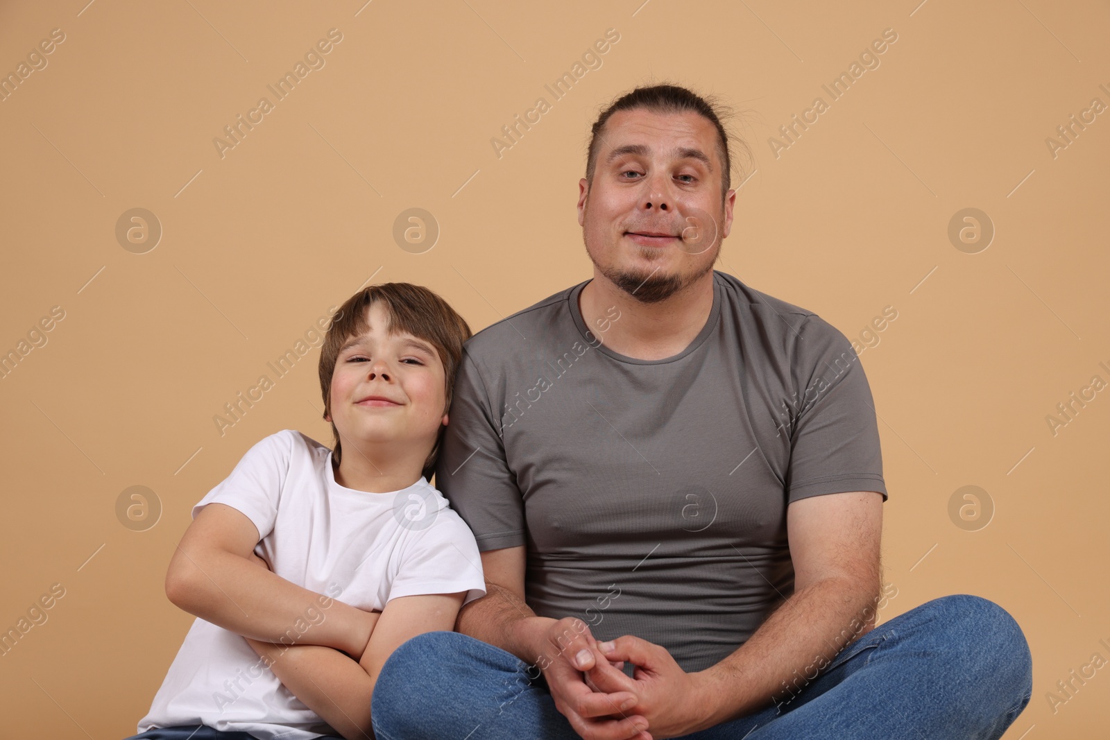 Father and his son on beige background Photo of Father and his son on beige background