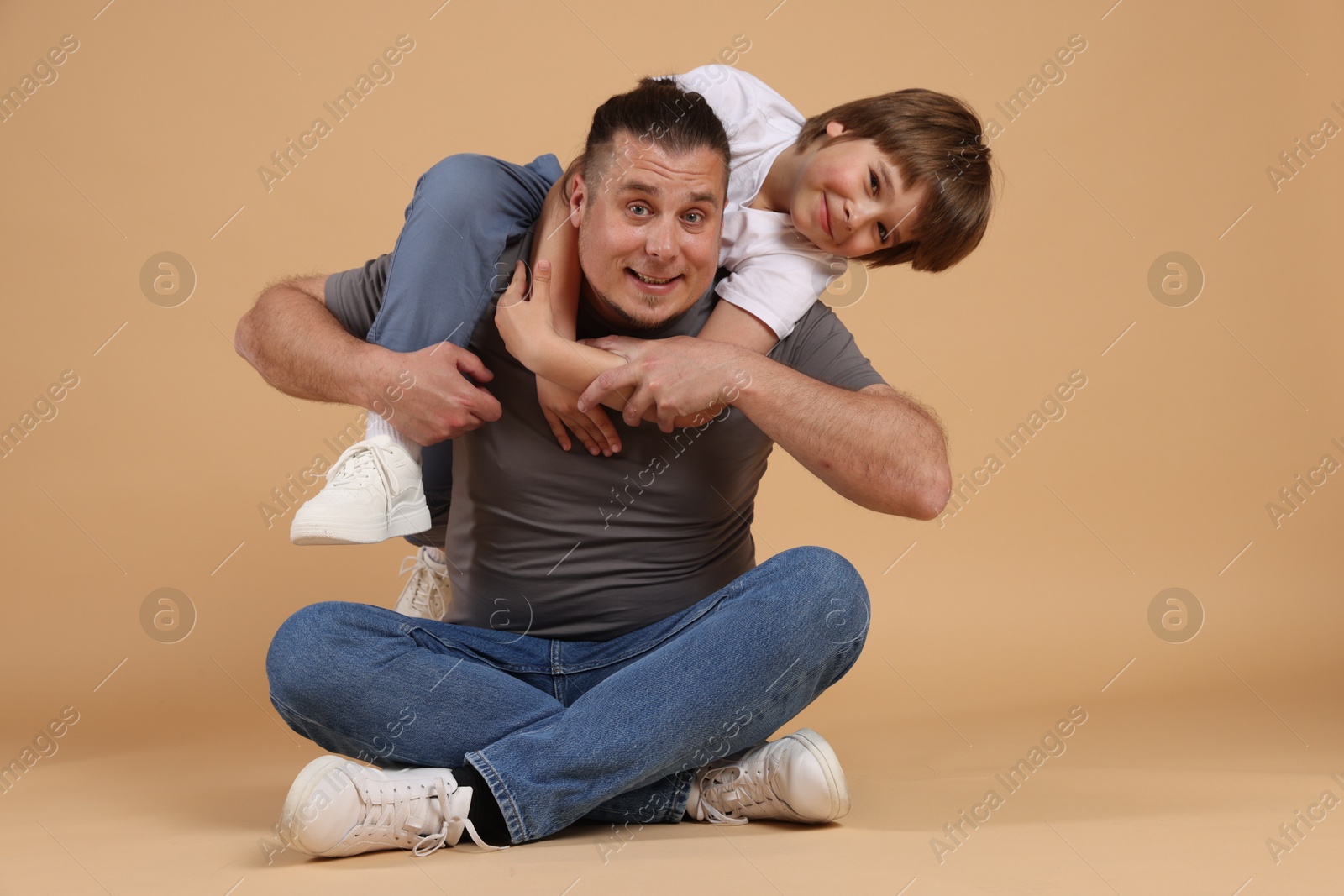 Father and his son on beige background Photo of Father and his son on beige background