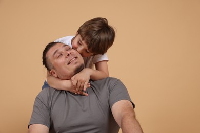 Photo of Father and his son on beige background, space for text