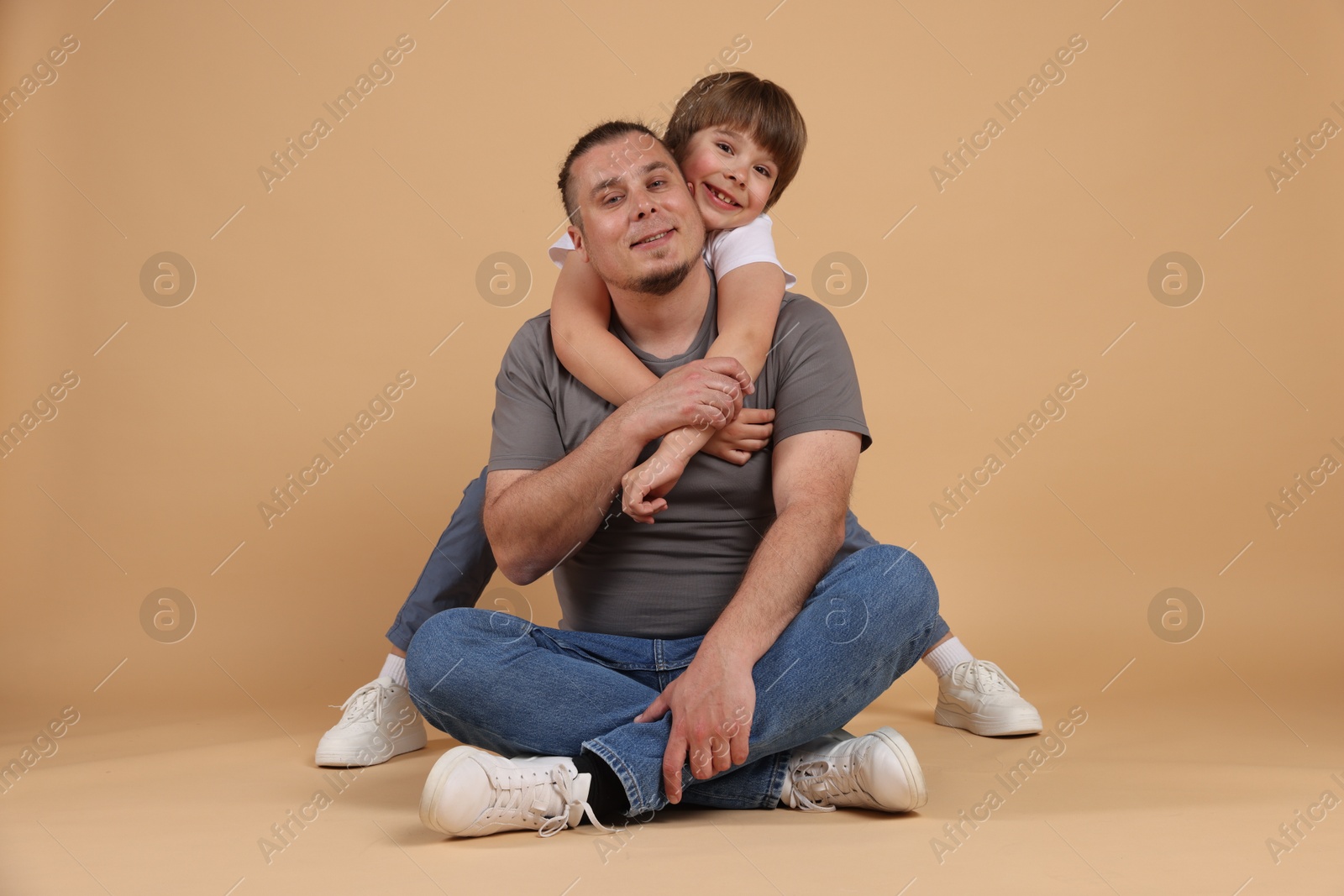 Father and his son on beige background Photo of Father and his son on beige background