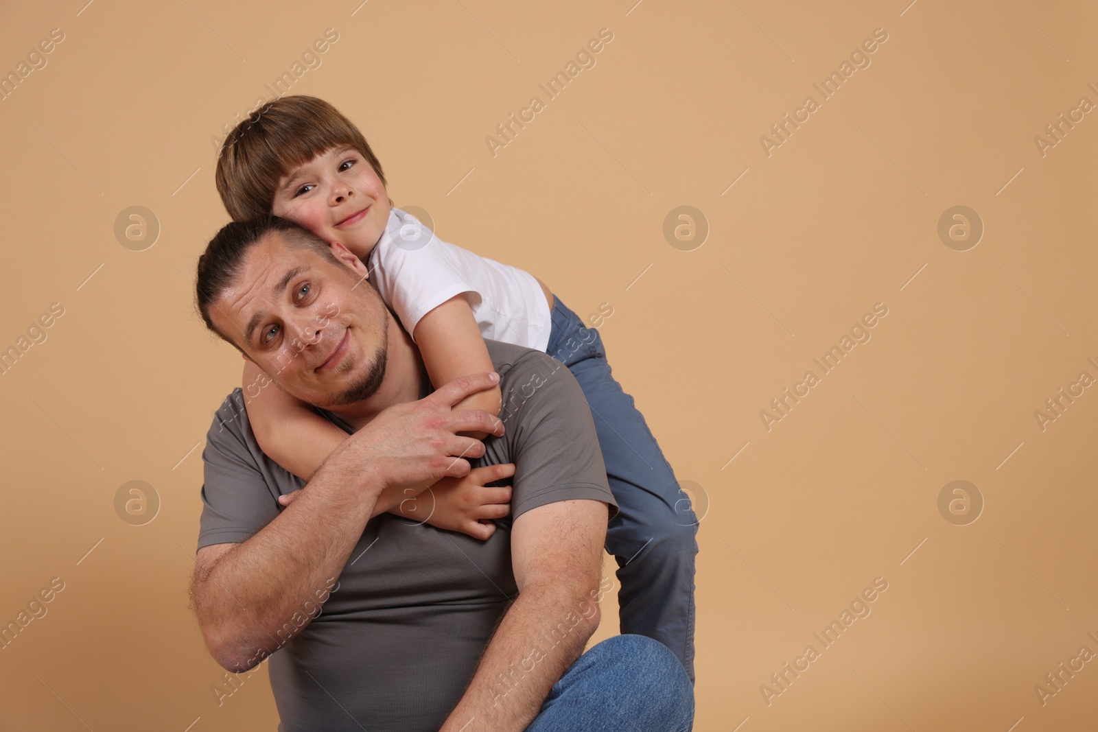 Father and his son on beige background, space for text Photo of Father and his son on beige background, space for text