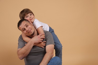 Photo of Father and his son on beige background, space for text