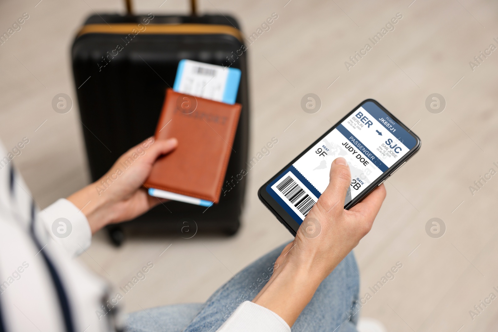 Tourist holding mobile phone with e-ticket for airplane and passport indoors, closeup Image of Tourist holding mobile phone with e-ticket for airplane and passport indoors, closeup