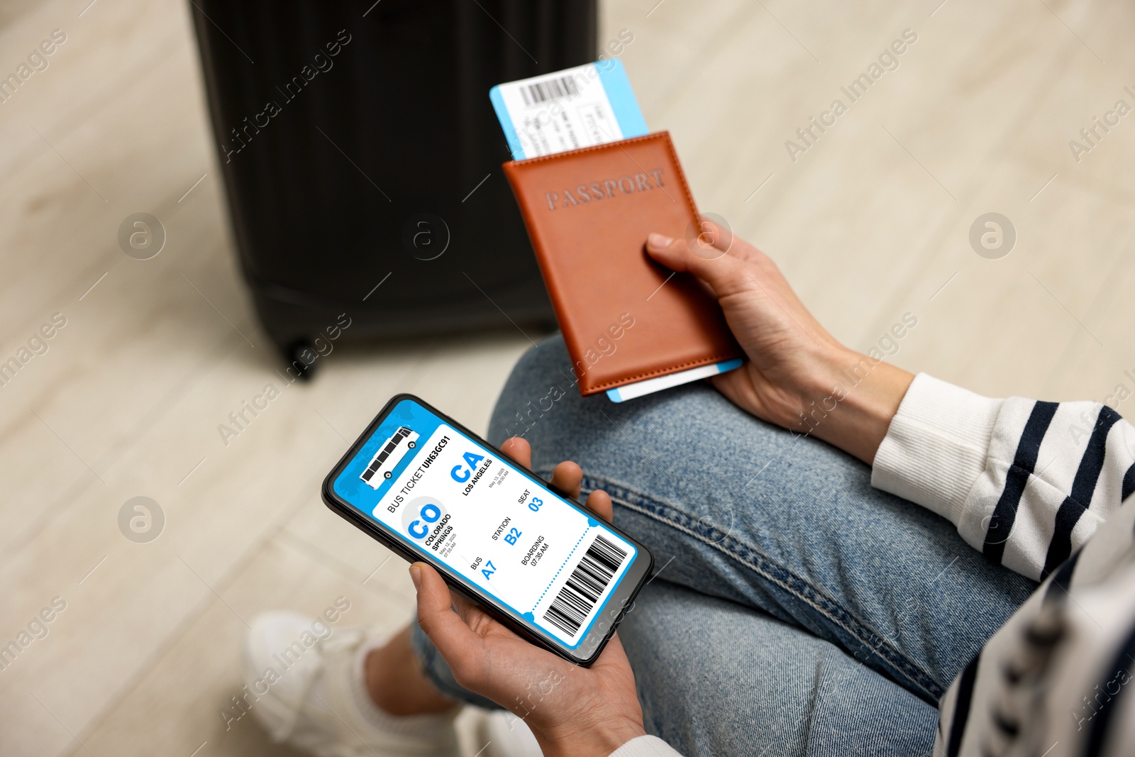 Tourist holding mobile phone with e-ticket for bus and passport indoors, closeup Image of Tourist holding mobile phone with e-ticket for bus and passport indoors, closeup