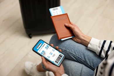 Image of Tourist holding mobile phone with e-ticket for bus and passport indoors, closeup