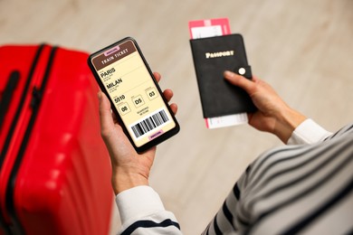 Image of Tourist holding mobile phone with e-ticket for train and passport indoors, closeup