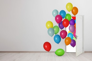 Image of Many bright balloons flying into open door. Festive decoration for birthday party or other celebration