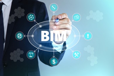 Image of Building information modeling. Man using virtual screen with abbreviation BIM and different icons, closeup
