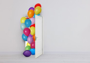 Image of Many bright balloons flying into open door. Festive decoration for birthday party or other celebration