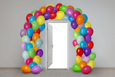 Image of Open door decorated with arch of bright balloons. Festive decoration for birthday party or other celebration
