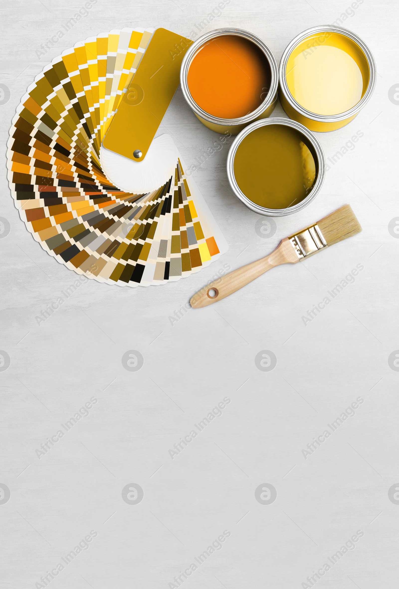 Cans with paint in shades of yellow, brush and color palette on white background, top view. Space for text Image of Cans with paint in shades of yellow, brush and color palette on white background, top view. Space for text