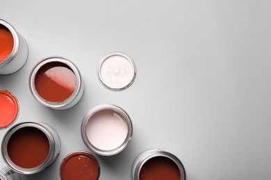 Image of Cans with paint in shades of red on light grey background, top view. Space for text