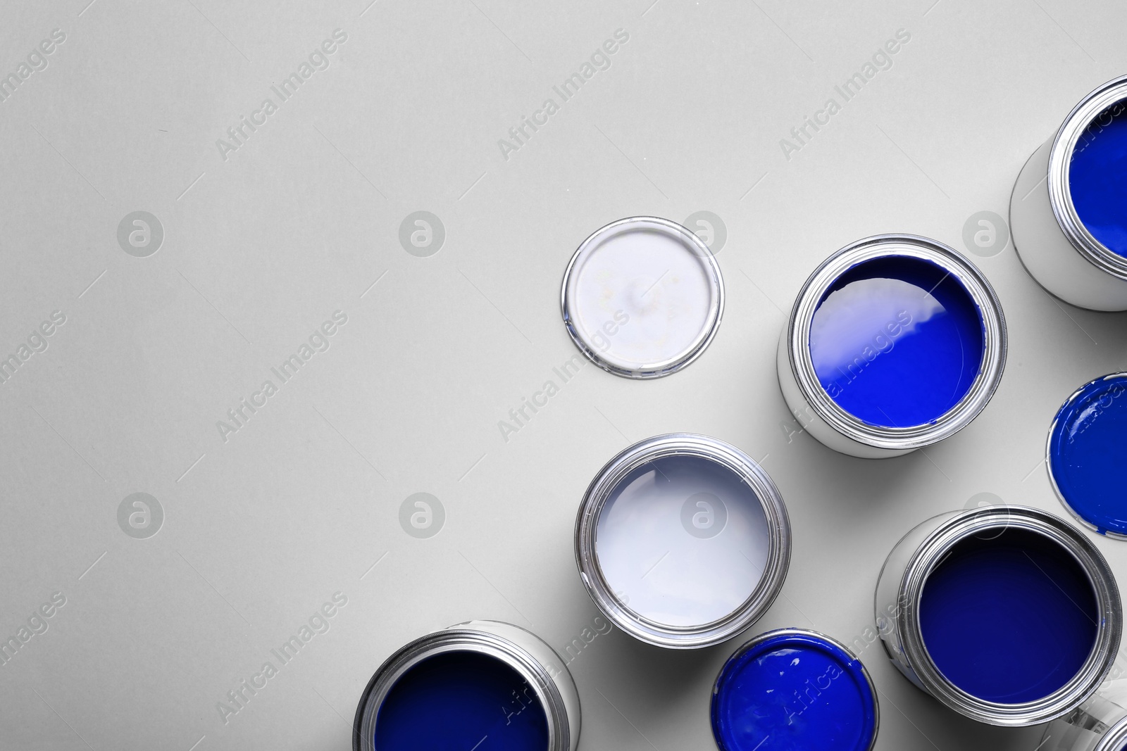 Cans with paint in shades of blue on light grey background, top view. Space for text Image of Cans with paint in shades of blue on light grey background, top view. Space for text