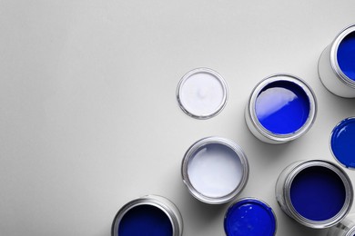 Image of Cans with paint in shades of blue on light grey background, top view. Space for text