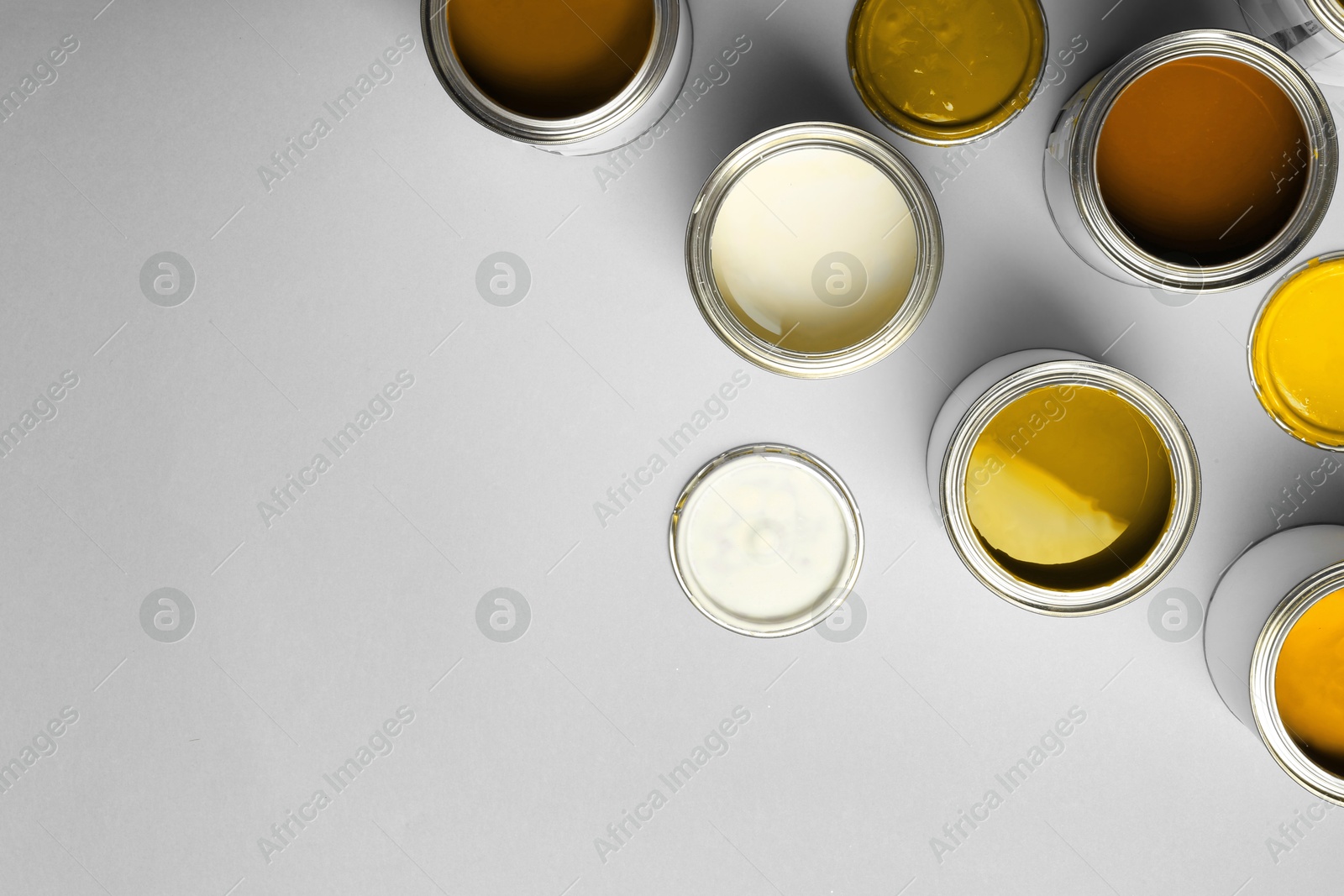 Cans with paint in shades of orange on light grey background, top view. Space for text Image of Cans with paint in shades of orange on light grey background, top view. Space for text