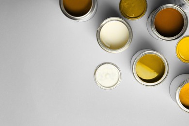 Image of Cans with paint in shades of orange on light grey background, top view. Space for text