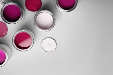 Image of Cans with paint in shades of pink on light grey background, top view. Space for text