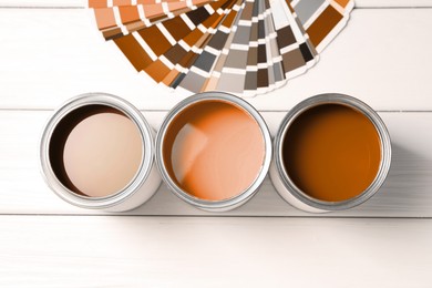 Image of Cans with paint in shades of brown and color palette on white wooden background, top view