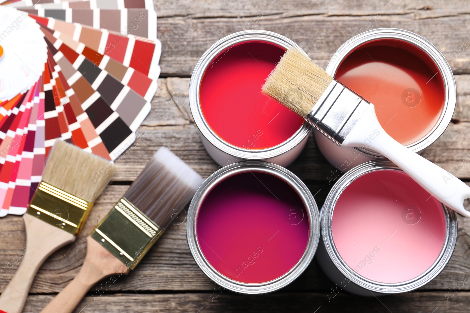 Cans with paint in shades of red, color palette and brushes on wooden background, top view Image of Cans with paint in shades of red, color palette and brushes on wooden background, top view