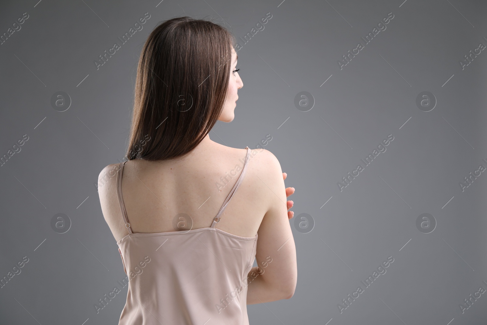 Beautiful woman on grey background, back view. Space for text Photo of Beautiful woman on grey background, back view. Space for text