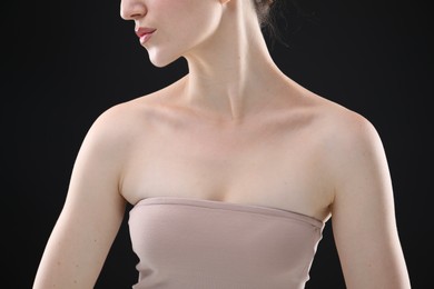 Photo of Woman with beautiful collarbones and neck on black background, closeup