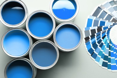 Image of Cans with paint in shades of blue and color palette on white background, top view