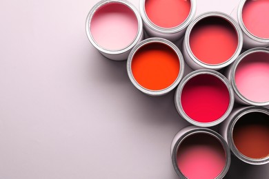Image of Cans with paint in shades of red on white background, top view. Space for text