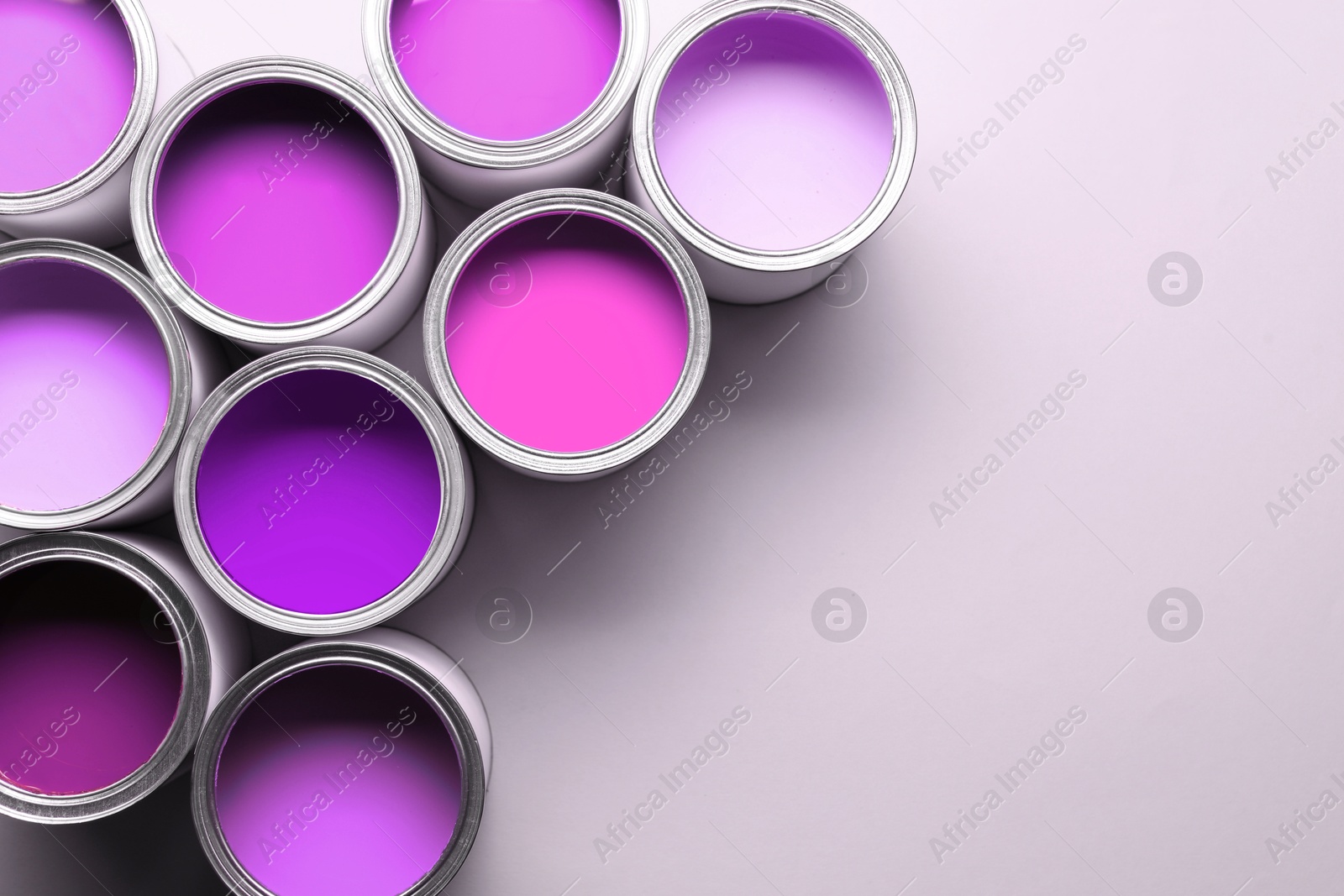 Cans with paint in shades of violet on white background, top view. Space for text Image of Cans with paint in shades of violet on white background, top view. Space for text