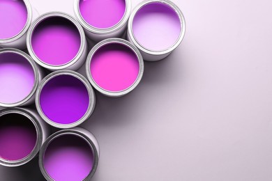 Image of Cans with paint in shades of violet on white background, top view. Space for text