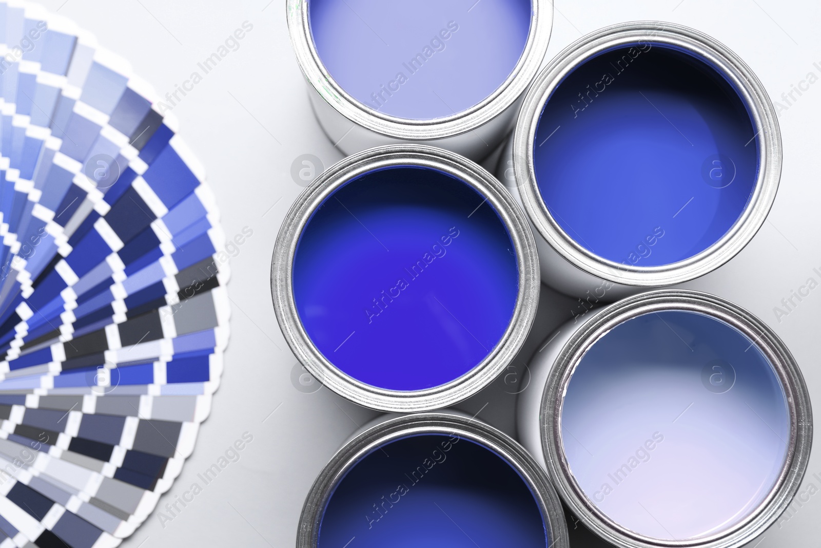 Cans with paint in shades of blue and color palette on white background, top view Image of Cans with paint in shades of blue and color palette on white background, top view
