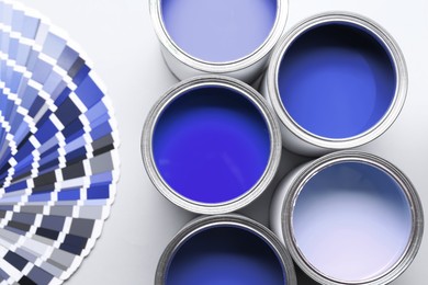 Image of Cans with paint in shades of blue and color palette on white background, top view