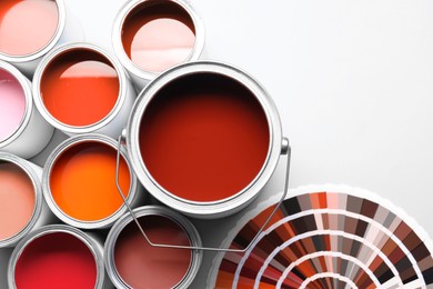 Image of Cans with paint in shades of red and color palette on white background, top view