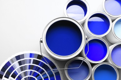Image of Cans with paint in shades of blue and color palette on white background, top view