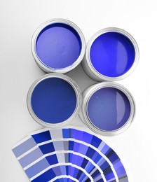 Image of Cans with paint in shades of blue and color palette on white background, top view