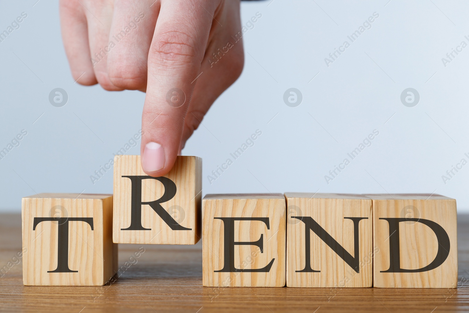 Man making word Trend with wooden cubes at table against light background, closeup Image of Man making word Trend with wooden cubes at table against light background, closeup