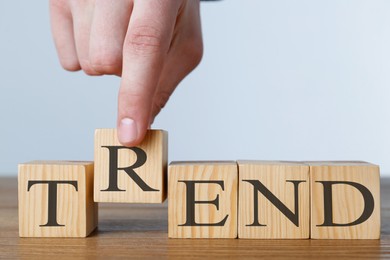 Image of Man making word Trend with wooden cubes at table against light background, closeup