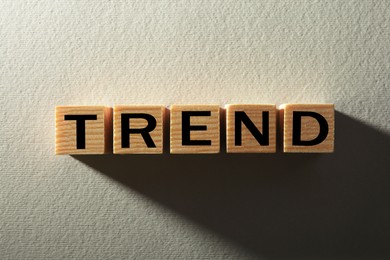 Image of Word Trend made of wooden cubes with letters on white textured background, top view