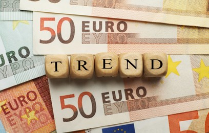 Image of Word Trend made of wooden cubes with letters on euro bills, top view