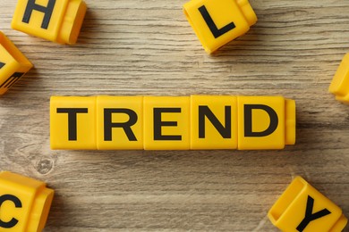 Image of Word Trend made of yellow cubes with letters on wooden background, top view