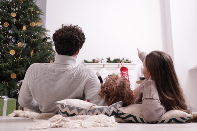 Photo of Family watching movie via video projector at home, back view