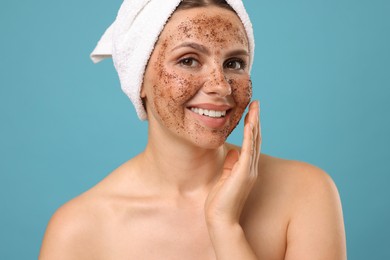 Photo of Smiling woman with body scrub on her face against light blue background