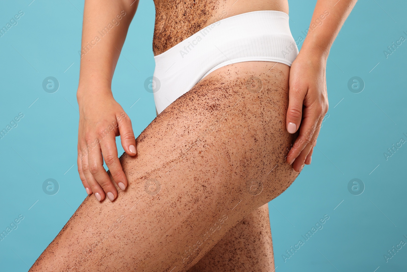 Woman with body scrub on her skin against light blue background, closeup Photo of Woman with body scrub on her skin against light blue background, closeup
