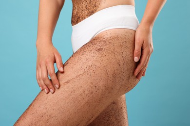 Photo of Woman with body scrub on her skin against light blue background, closeup